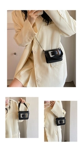 Macro detail of mini black leather bag with silver buckle and metal chain strap