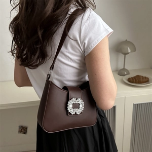 Chocolate brown underarm shoulder bag with luxury crystal buckle on a minimalist backdrop