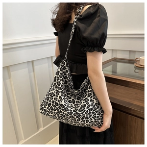 Close-up of leopard print canvas hobo bag carried by model in a casual setting