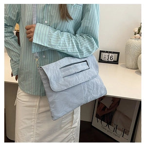 Light blue pleated crossbody bag with slim strap shown on model in a stylish setting