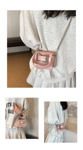 Close-up of a pale pink mini crossbody bag with a large silver buckle and chain strap