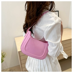 Close-up of pink patent leather shoulder bag with a glossy mirror finish on a person