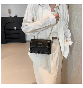 Detail of black crossbody bag with multi-layer wavy ruffle design and gold chain strap