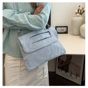 Detail of light blue pleated PU leather crossbody bag with silver hardware and top handle
