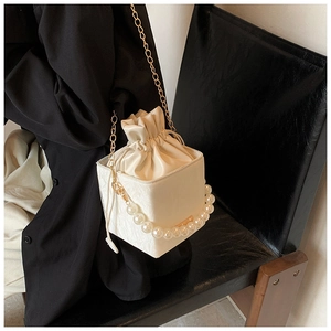 Detailed view of white cube bucket bag with drawstring closure and large pearl handle