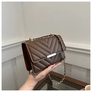 Nahaufnahme einer dunkelbraun gesteppten quadratischen Tasche mit goldener Schnalle