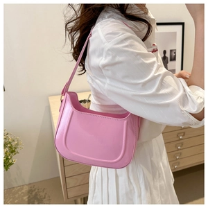 Chic pink glossy underarm bag shown with white outfit in a stylish indoor setting