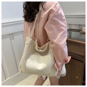 Detail of the woven straw tote bag featuring a creamy leather pocket and slim straps