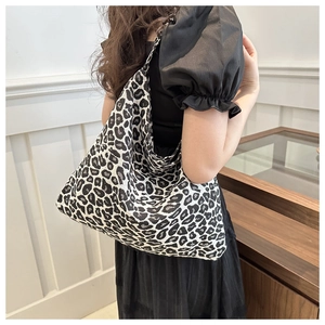 Detailed side view of high-capacity leopard print nylon tote bag worn by a model