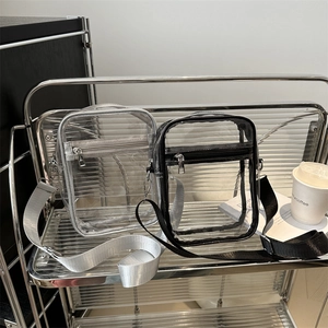 Waterproof clear PVC crossbody bag with black and silver trim on a modern metal shelf