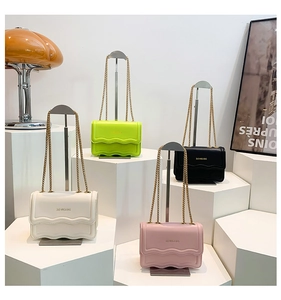 Detail of four colorful flap crossbody bags with wavy stitching and gold chain straps