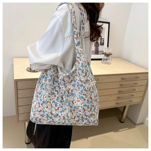 Floral canvas tote bag with blue and orange flowers on a wide shoulder strap in home setting