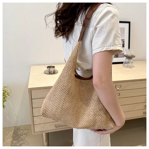 Close-up of woven straw shoulder bag featuring a brown leather strap and mesh texture
