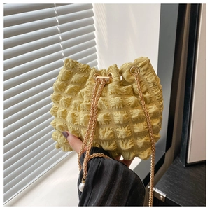 Dettaglio borsa a secchiello gialla con texture a bolle e catena dorata con perle
