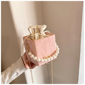 Detail of pink pleated bucket bag featuring pearl handle and gold chain strap