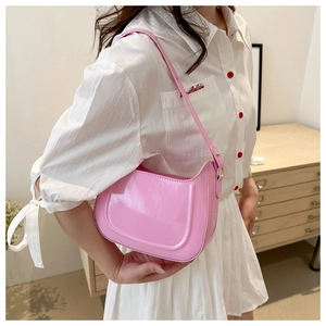 Detail of pink patent leather hobo bag worn on shoulder over white shirt outfit