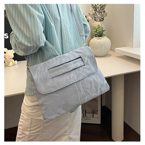Detail of light blue pleated shoulder bag featuring a rectangular cutout handle and strap