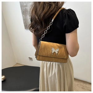 Detail of khaki pleated shoulder bag with silver butterfly buckle and chain strap