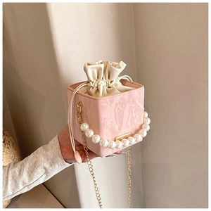 Detail of pink pearl handle bucket bag with silk drawstring and gold chain strap