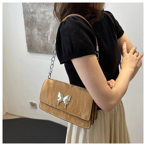 Detail of crinkled leather shoulder bag with silver butterfly buckle on model