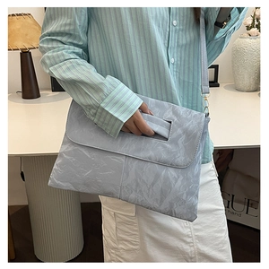 Gros plan du sac bandoulière bleu clair à texture froissée avec poignée intégrée