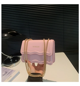 Detailed view of pink crossbody bag with scalloped edges and chunky gold chain strap