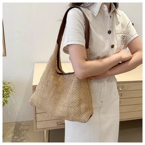 Close-up of woven straw shoulder bag with dark brown leather strap for summer