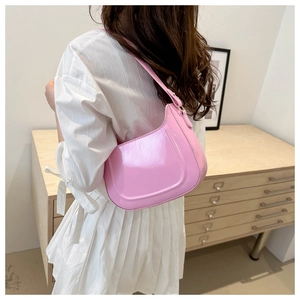 Rear view of model wearing pink patent leather hobo bag with glossy finish and hobo design