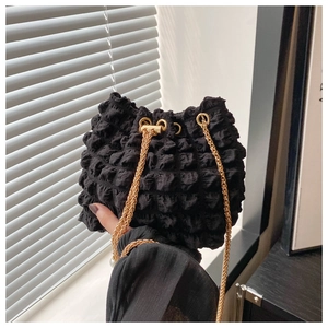 Dettaglio della trama a bolle nera e della catena dorata di questa borsa a secchiello moda
