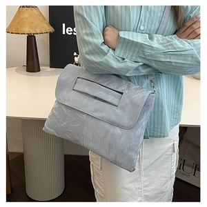 Macro detail of light blue pleated texture on a minimalist large capacity shoulder bag