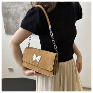 Close-up of a yellow faux leather shoulder bag with a silver butterfly metal clasp