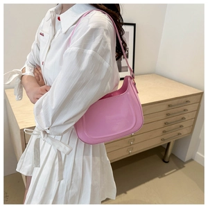 Detailed side view of pink patent leather shoulder bag with glossy finish on a model