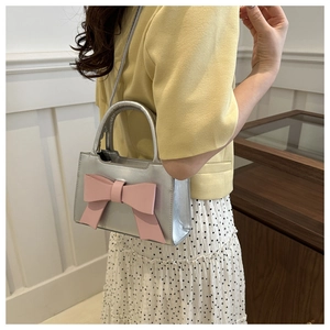 Model view of silver mini square bag with a large pink bow and slender strap