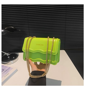 Detail of neon green wavy textured PU leather bag with elegant gold metal chain strap