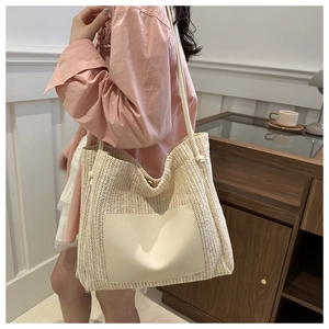 Close-up of woven straw tote bag with smooth faux leather pocket and shoulder straps