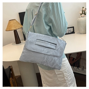 Détail du sac enveloppe bleu clair à texture froissée avec fine bandoulière et fermoir