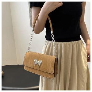 Close-up of caramel shoulder bag with silver butterfly buckle and chain strap detail