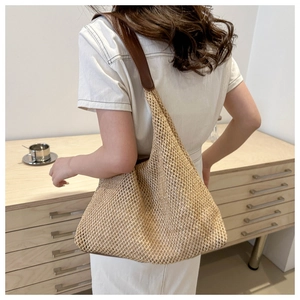 Detail of beige woven straw tote with brown leather strap and openwork mesh texture