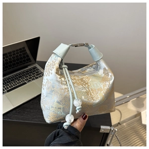 Détail du sac à main en soie bleue avec motifs dorés et fermoir argenté élégant