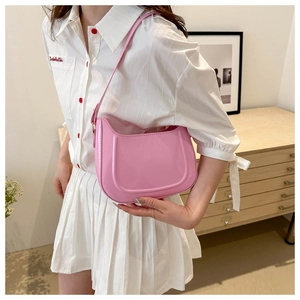 Close-up of a pink glossy hobo bag with a U-shaped silhouette and slim shoulder strap