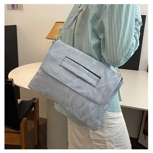 Close-up of light blue crossbody bag with unique crinkled texture worn by a model