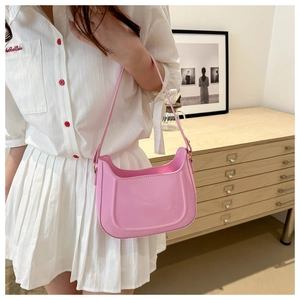 Chic pink semi-circular leather shoulder bag worn over the shoulder with minimalist style
