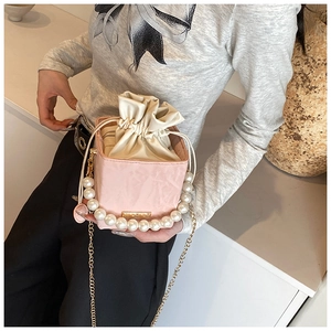 Detail of pink PU suede bucket bag with pearl handle and golden chain strap