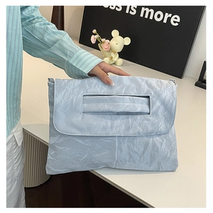 Gros plan du sac à bandoulière plissé bleu clair avec poignée découpée et rabat