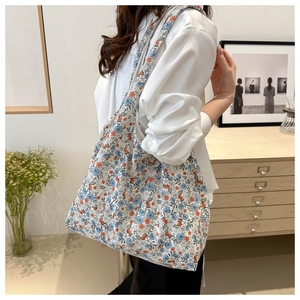 Close-up of floral canvas tote bag with blue and orange patterns on a model shoulder