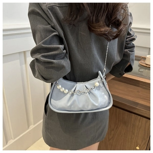 Close-up of light blue pleated leather bag featuring elegant pearl and metal flower chain