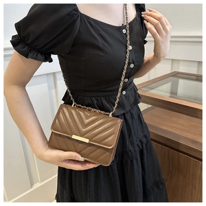 Detail der braunen Stepptasche im Chevron-Muster mit goldener Kette und Verschluss