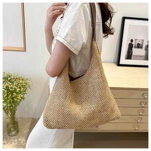 Detail of hand-woven straw shoulder bag with dark brown leather straps for summer beach