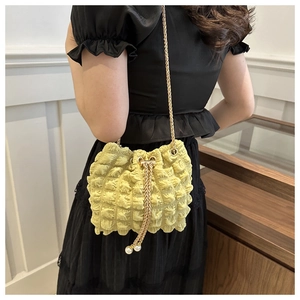 Dettaglio borsa gialla a pieghe con catena dorata e perle eleganti sulla coulisse