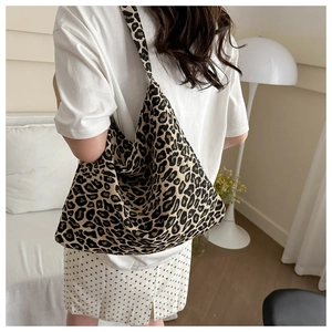 Detailed view of leopard print nylon hobo tote bag worn over the shoulder by a model